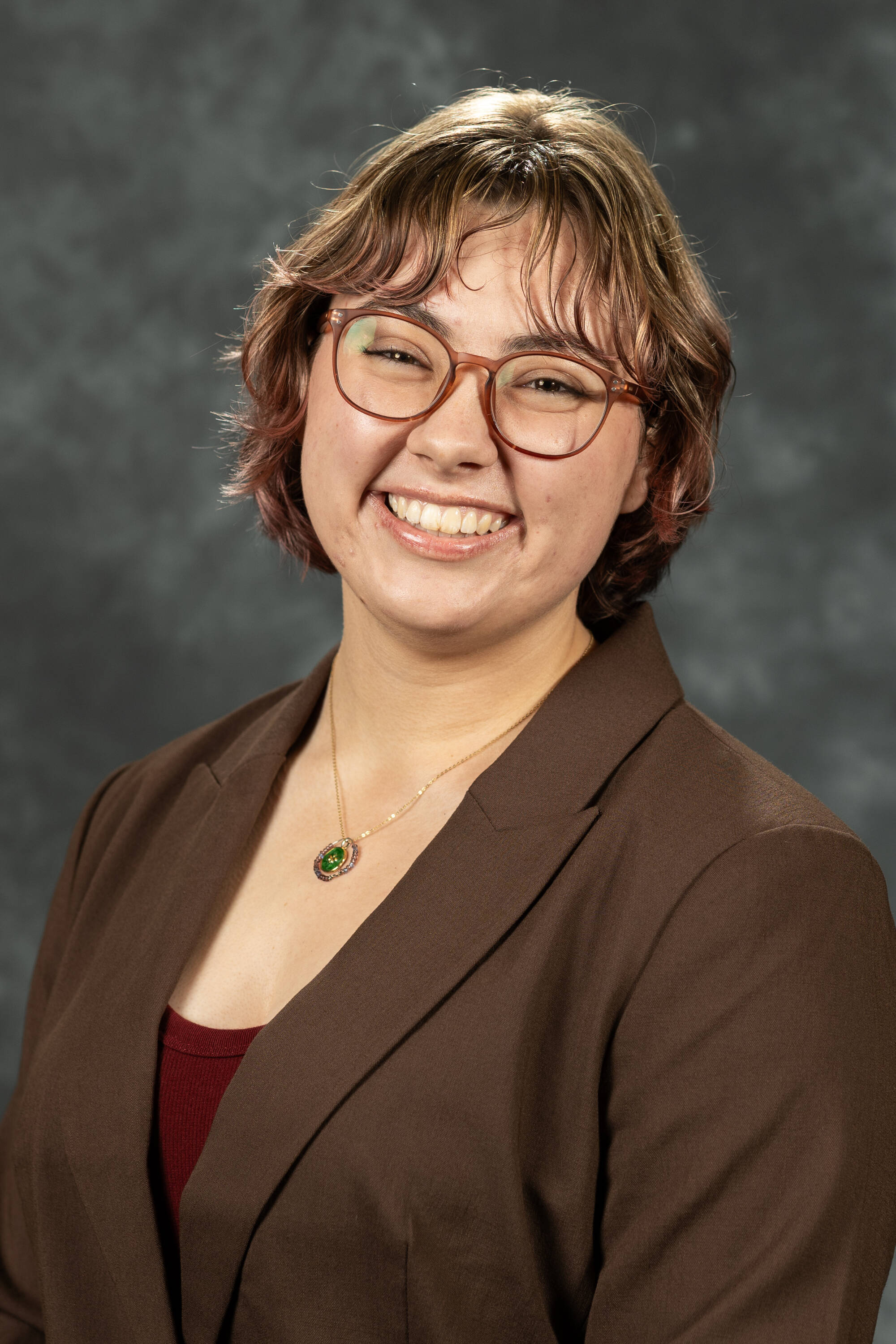 Sophie Gemmen smiling in a red shirt with brown blazer.